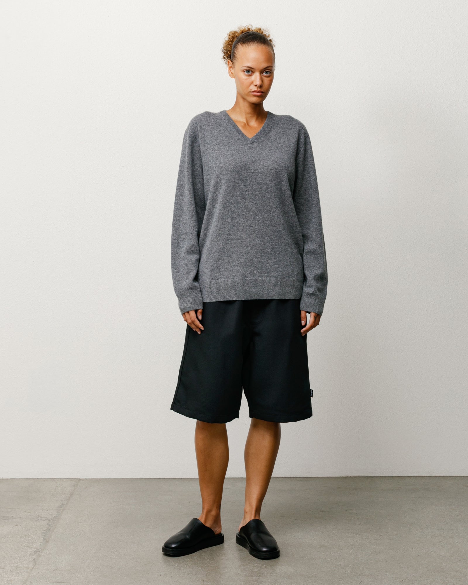 Black baggy knee-length shorts with relaxed unisex fit, shown on model front view.