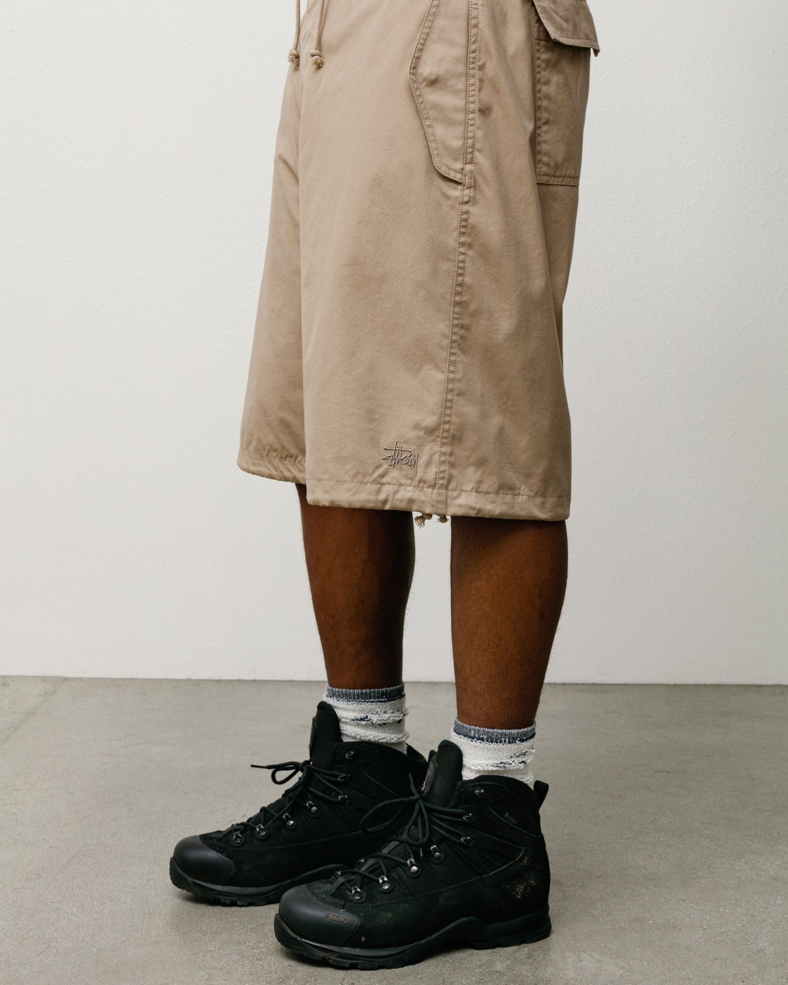 Khaki baggy cotton-nylon Surplus Short with drawcord hem and Stüssy logo, styled with black boots