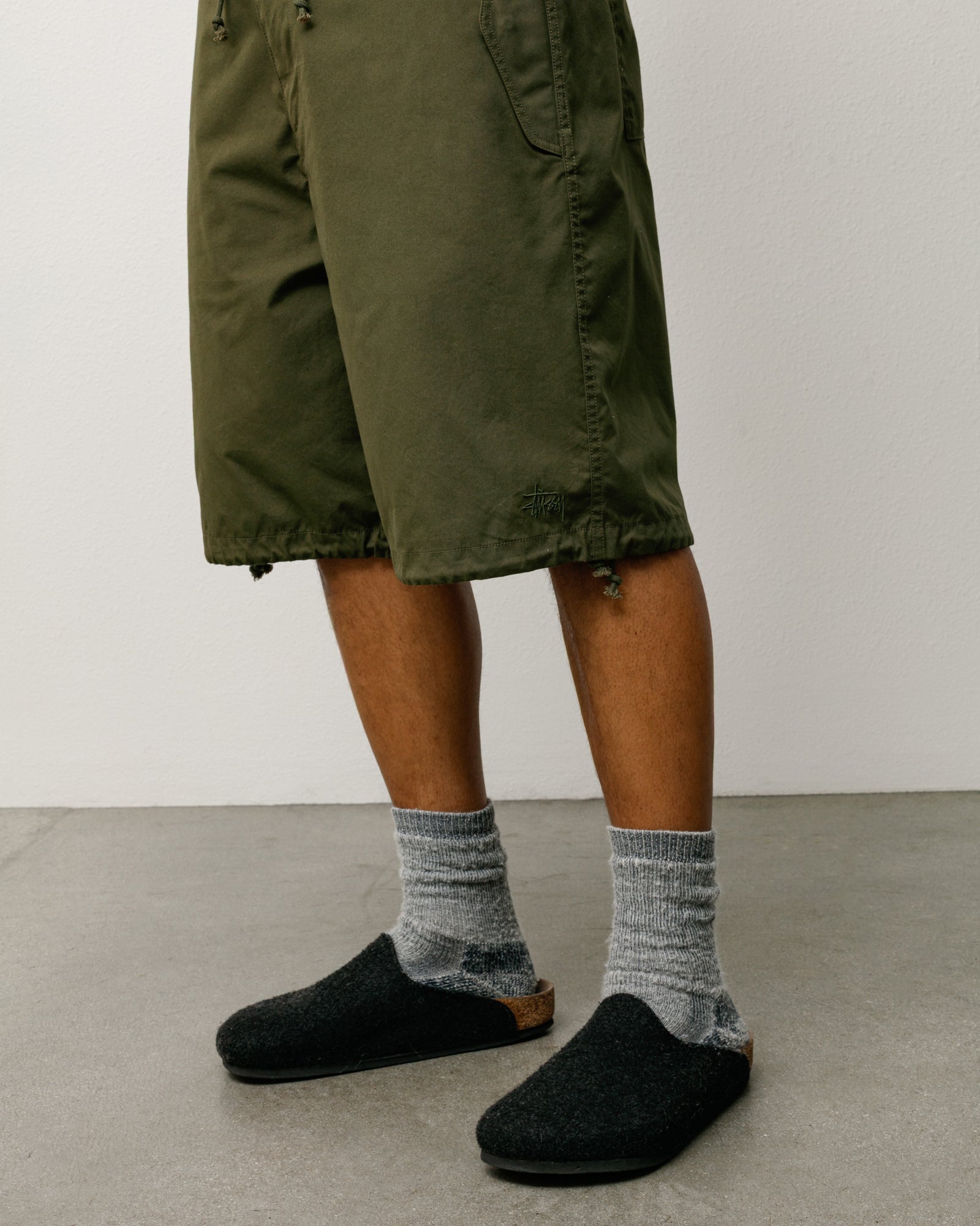 Olive baggy knee-length shorts with drawcord hems and small logo at hem, cropped on model legs