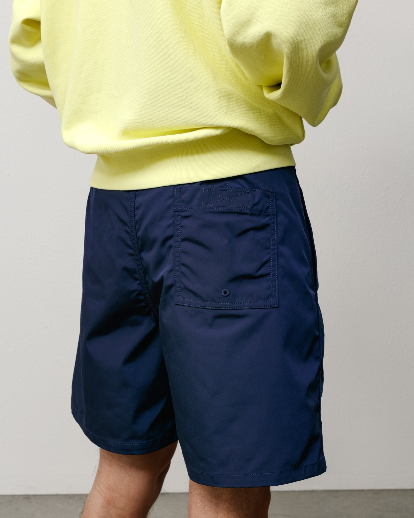 Navy blue board shorts on model, polyester finish with rear patch pocket and drainage eyelet.