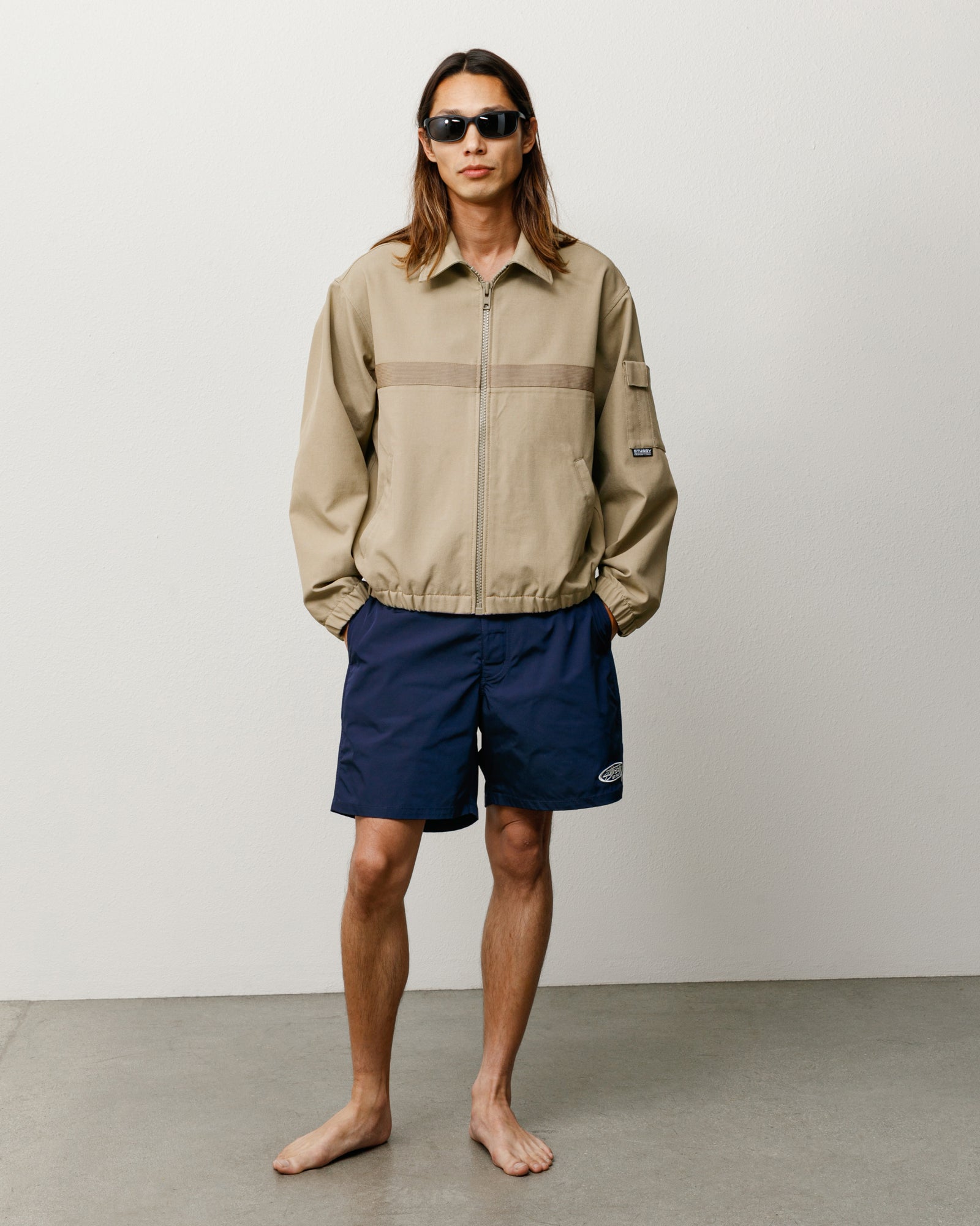 Blue board shorts, unisex regular fit with logo at left hem, on-model front view
