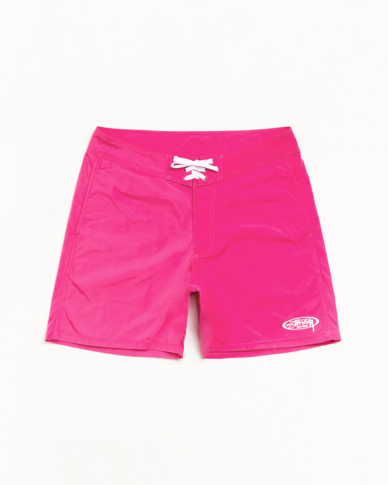 Bright pink board shorts with white lace-up waist and small logo at hem