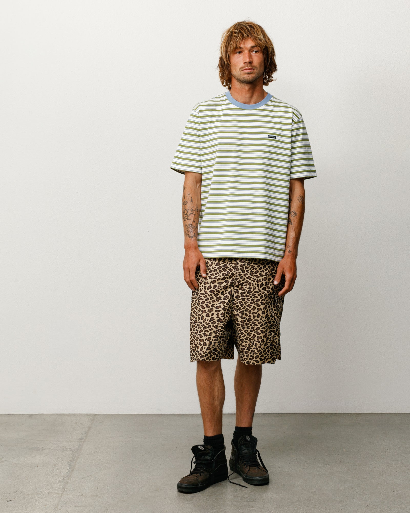 Green and white striped short-sleeve tee with blue ribbed crew collar, model front view