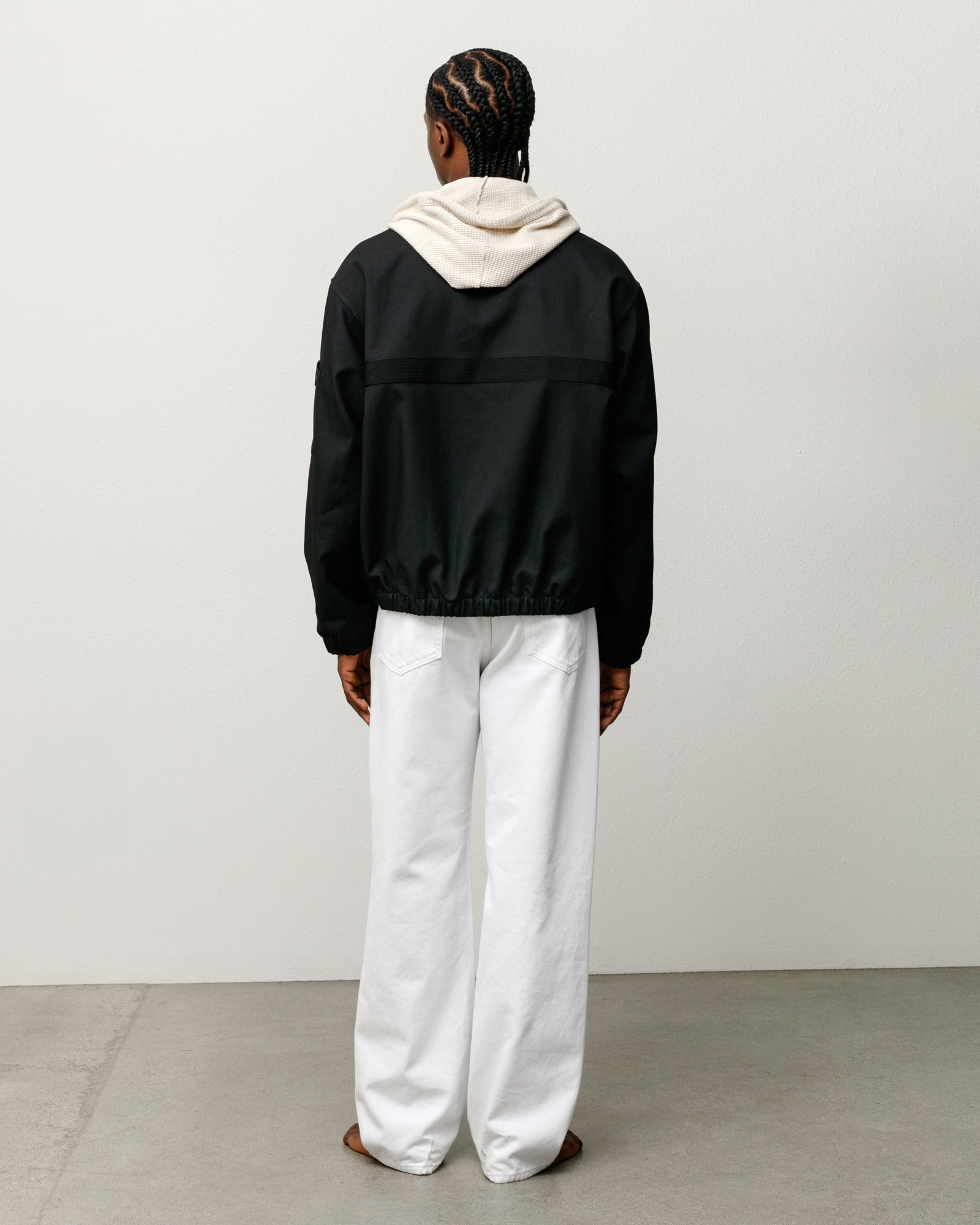Black mechanic jacket, back view with boxy fit and elastic hem, styled over a hoodie