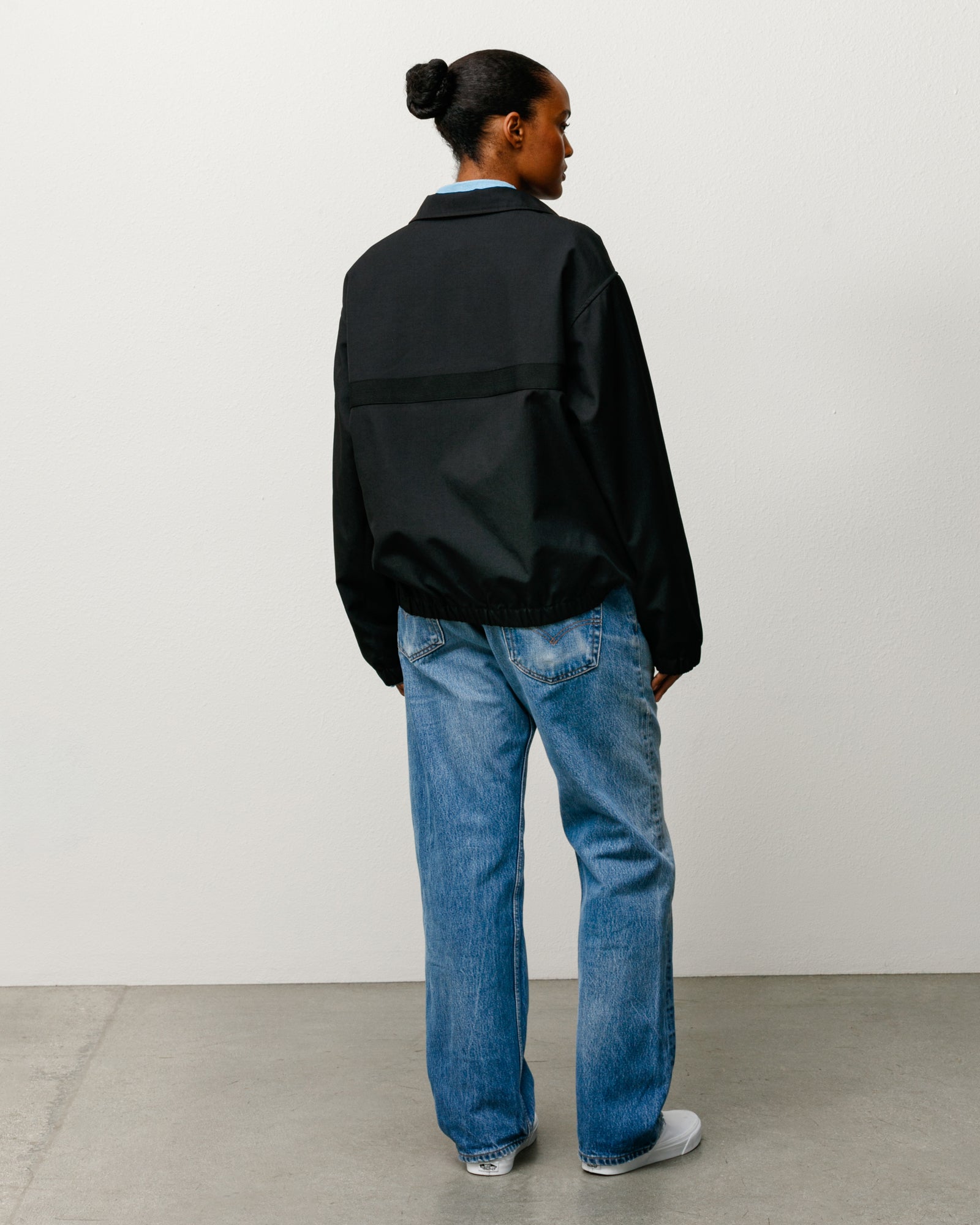 Black mechanic jacket, long sleeve with elastic hem and back panel detail, rear view on model