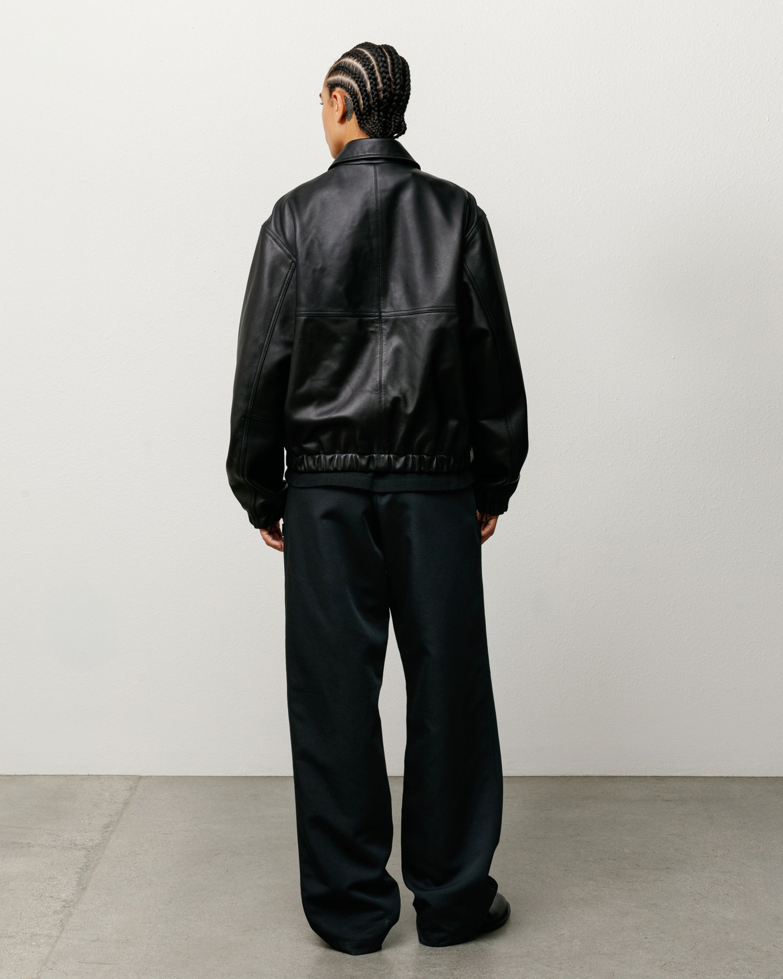 Black leather work jacket, back view on model with elastic hem and relaxed fit