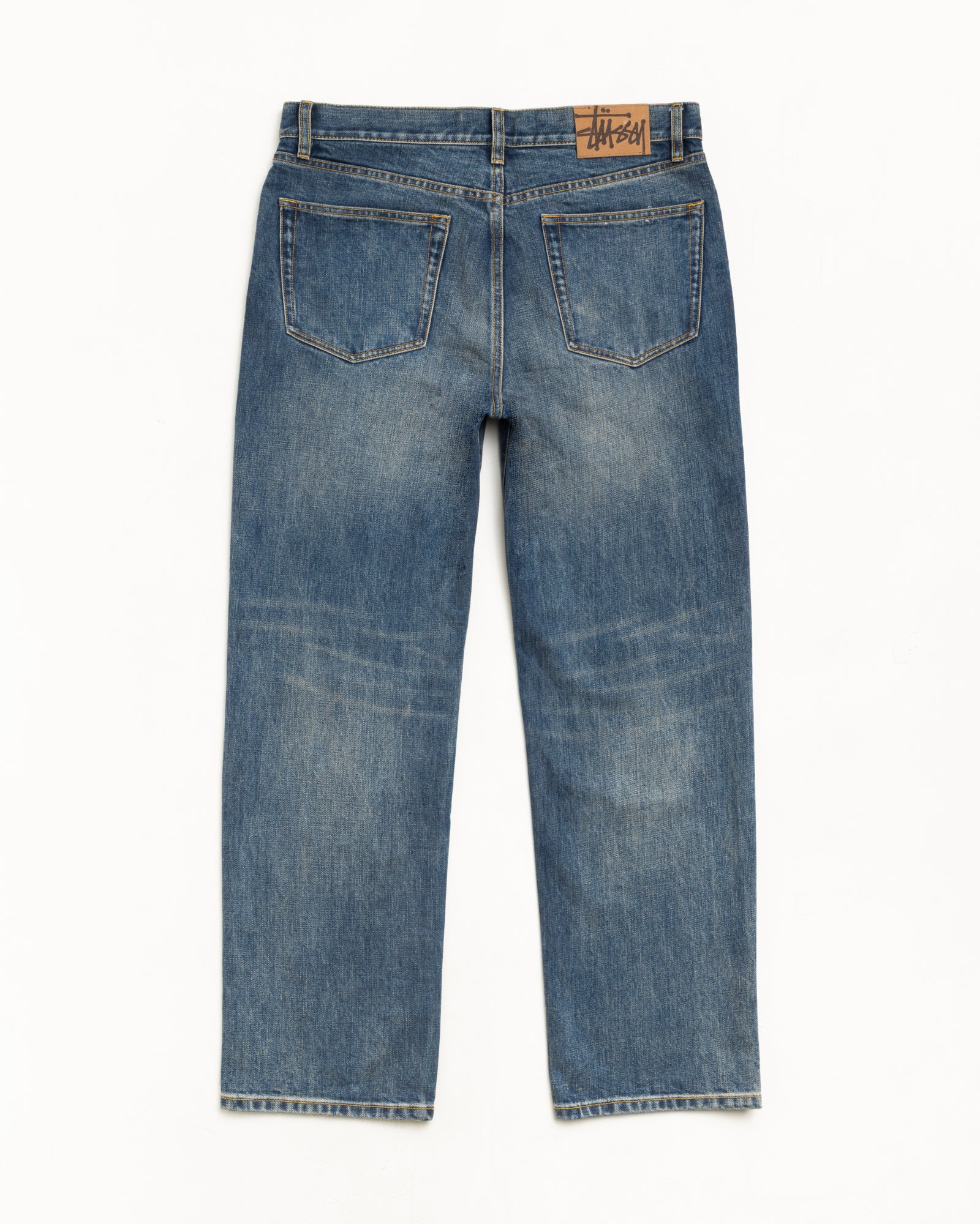 Blue slub denim straight-leg jeans, back view with suede Stüssy logo patch