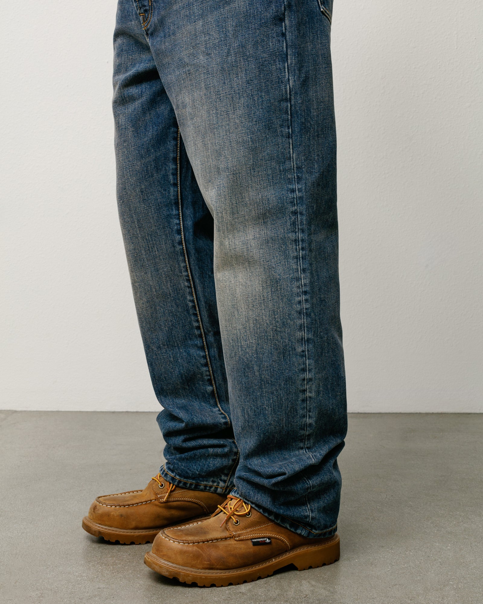Blue slub denim regular straight-fit jeans on model with brown moc‑toe boots.