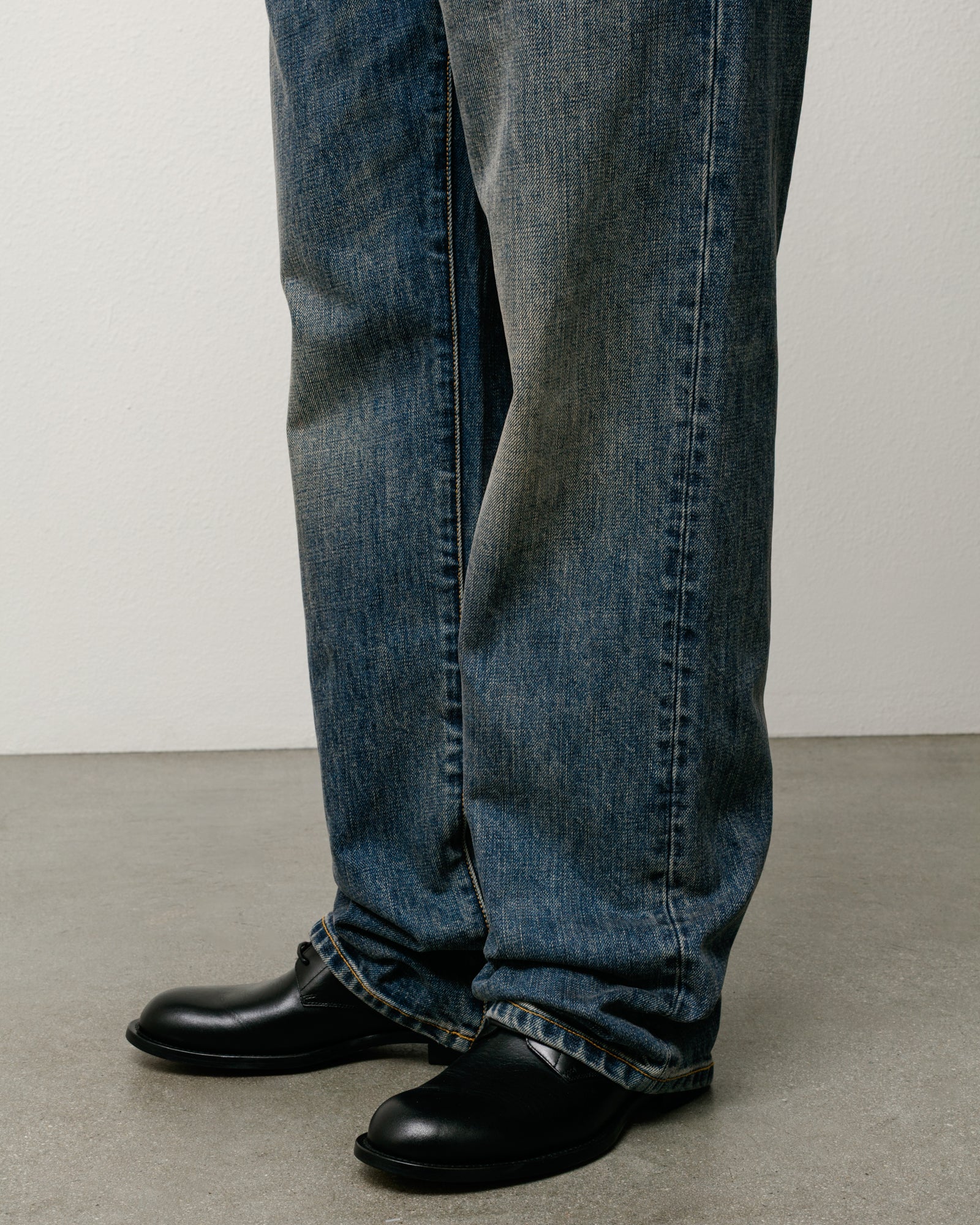 Blue slub denim straight-leg jeans worn on model, stacked over black shoes
