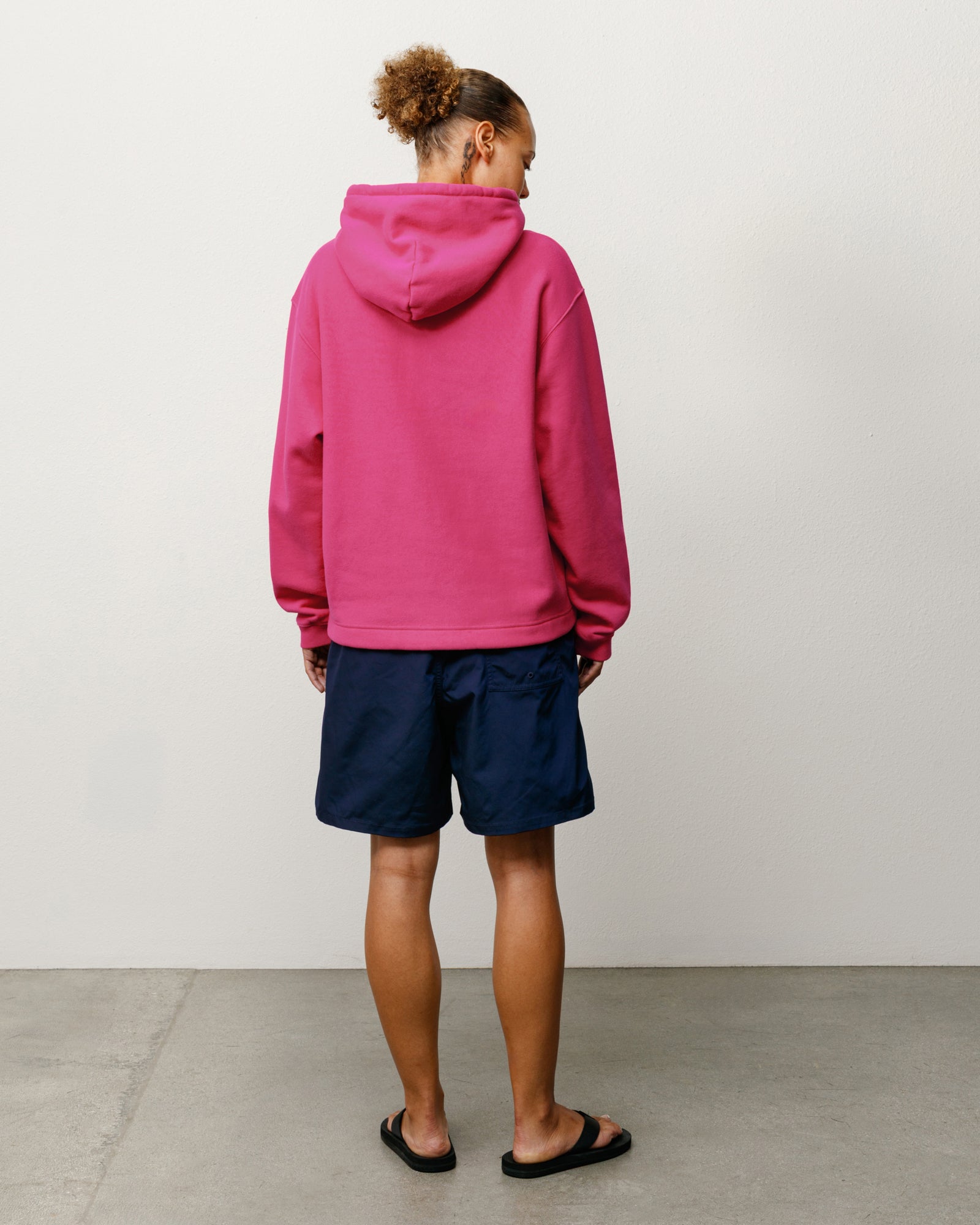 Pink pullover hoodie, back view on model with hood and ribbed hem