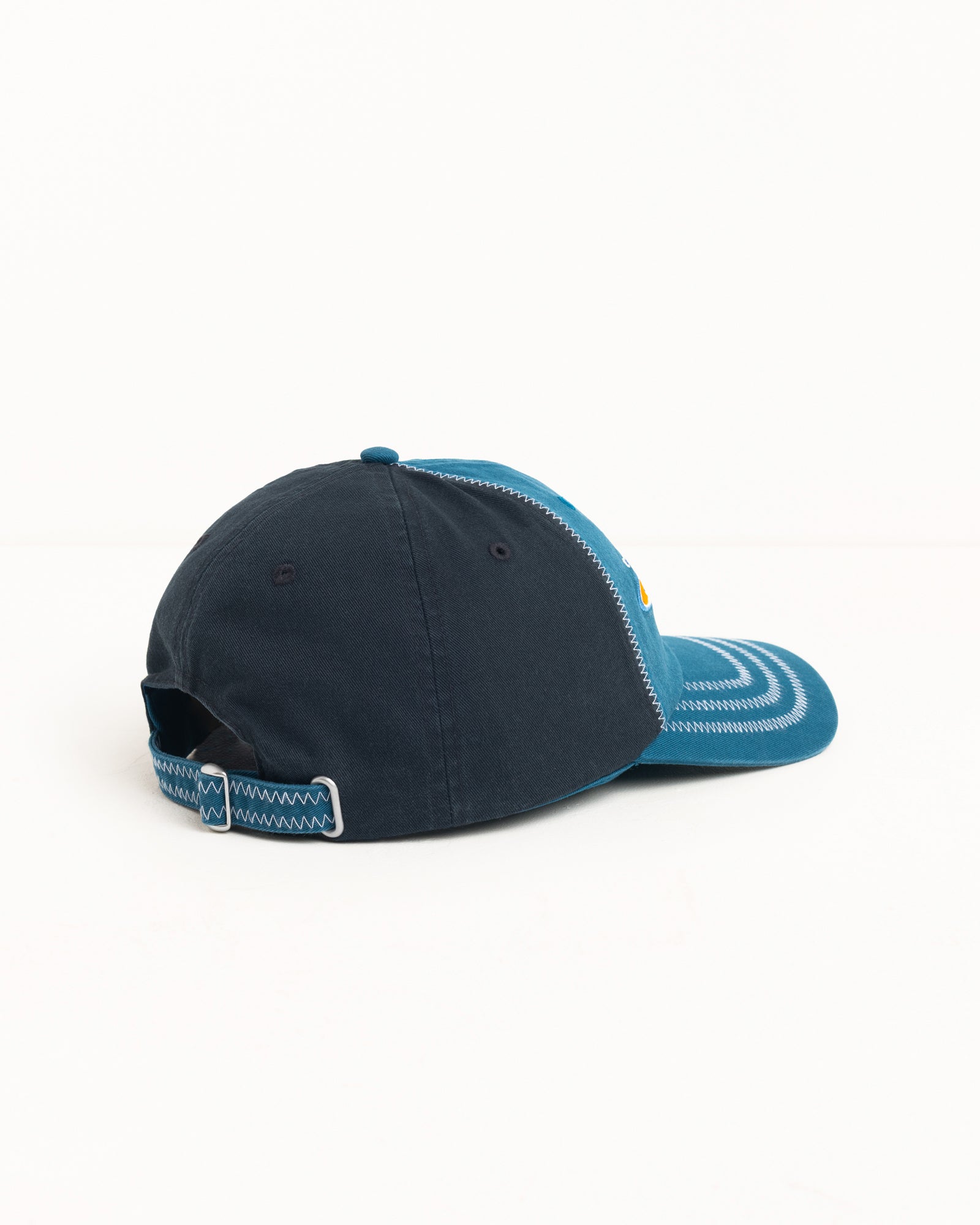 Blue two-tone cotton twill cap, back view, with zig-zag stitching and adjustable strapback closure