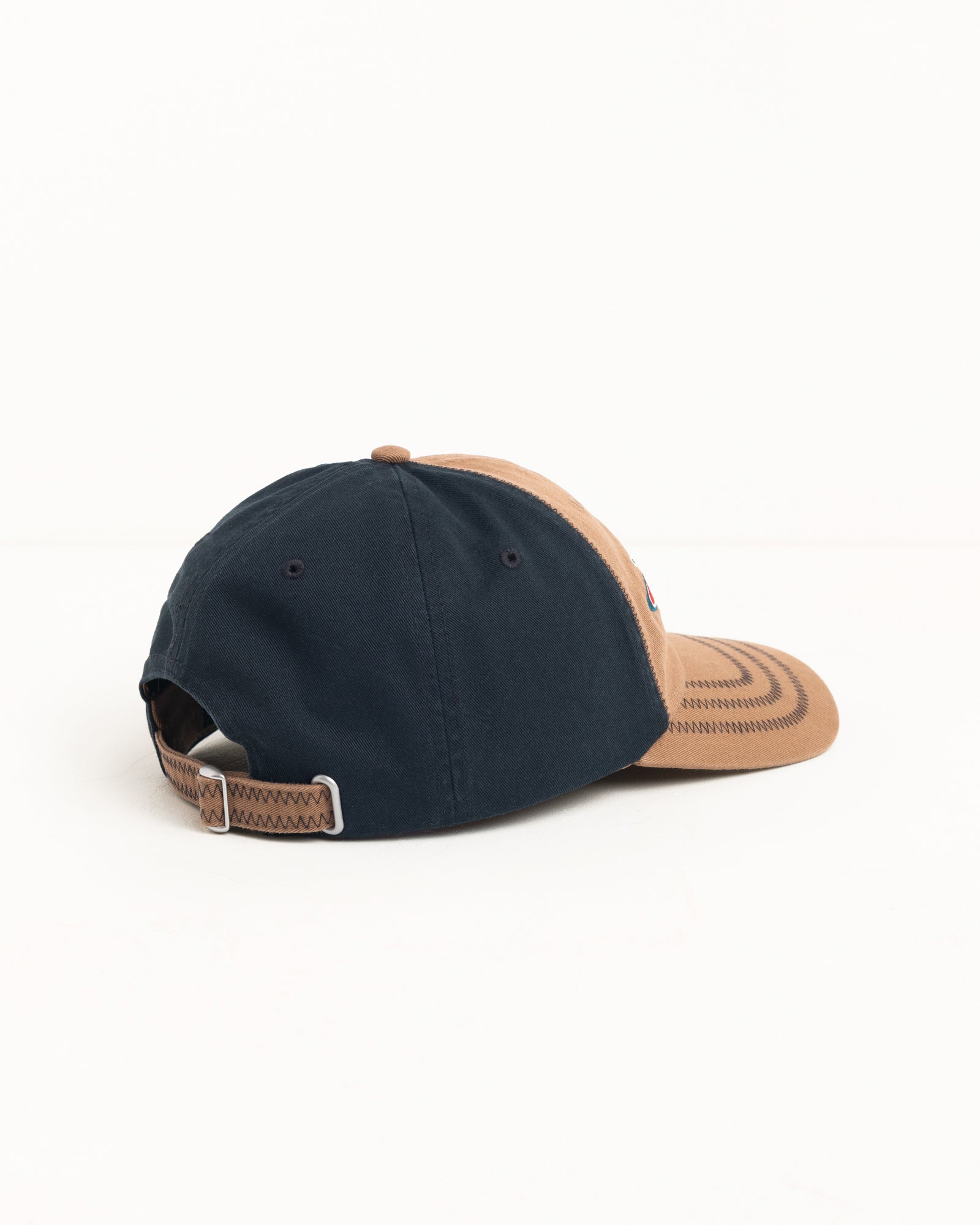 Low Profile cotton twill cap in brown and navy with zig‑zag stitched brim and metal strapback