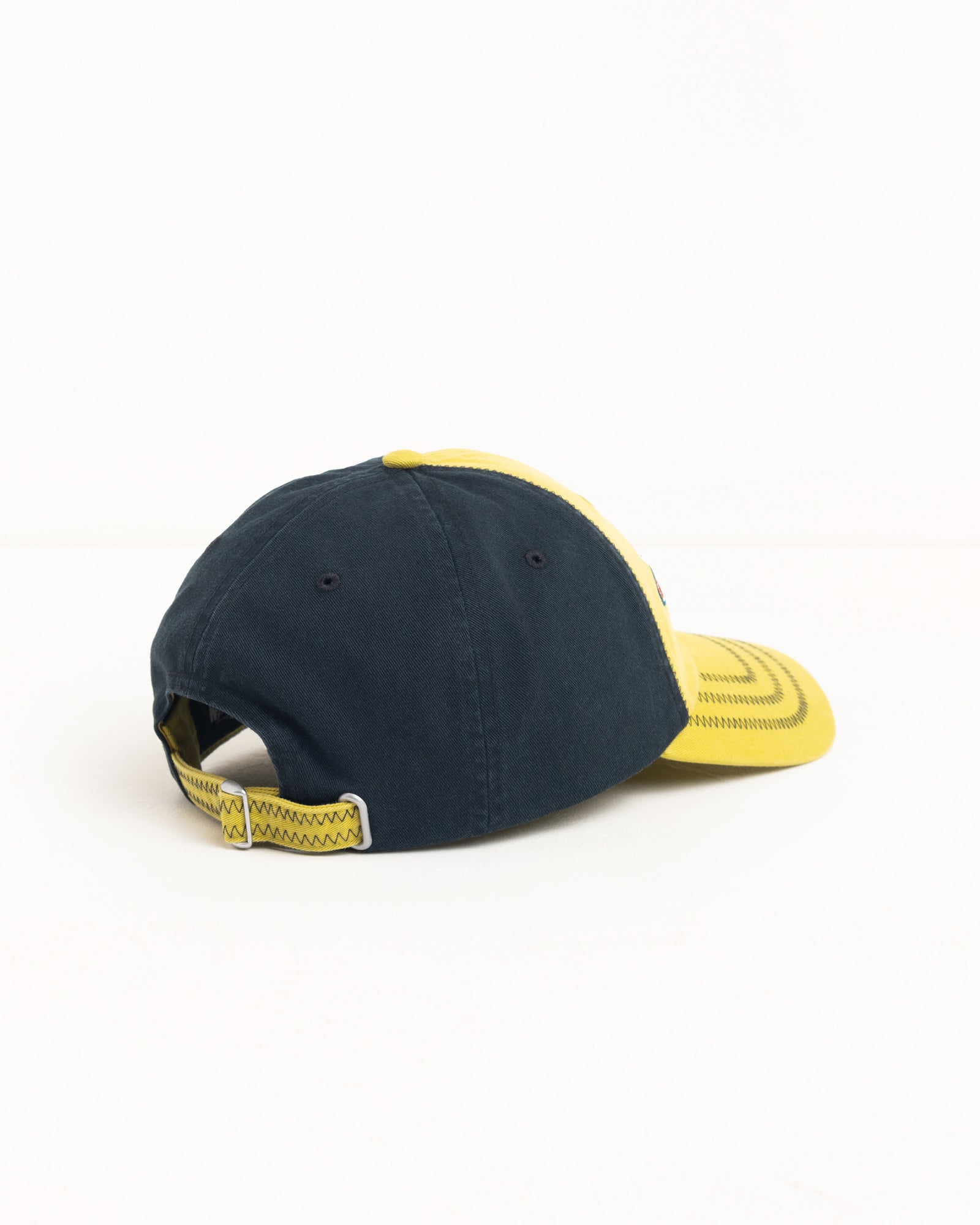 Lime cotton twill six-panel cap with navy back, zig-zag stitching, pre-curved brim and metal strapback