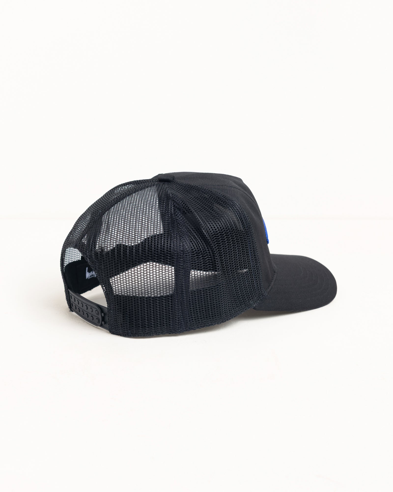 Black trucker cap with mesh back, curved brim and snapback fastening