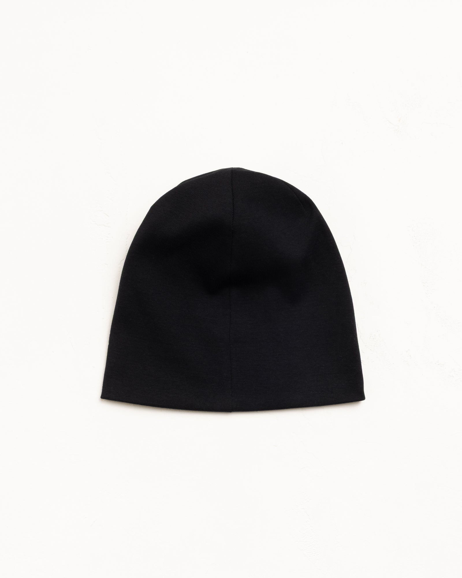 Black cotton jersey skullcap beanie, flat lay on white background