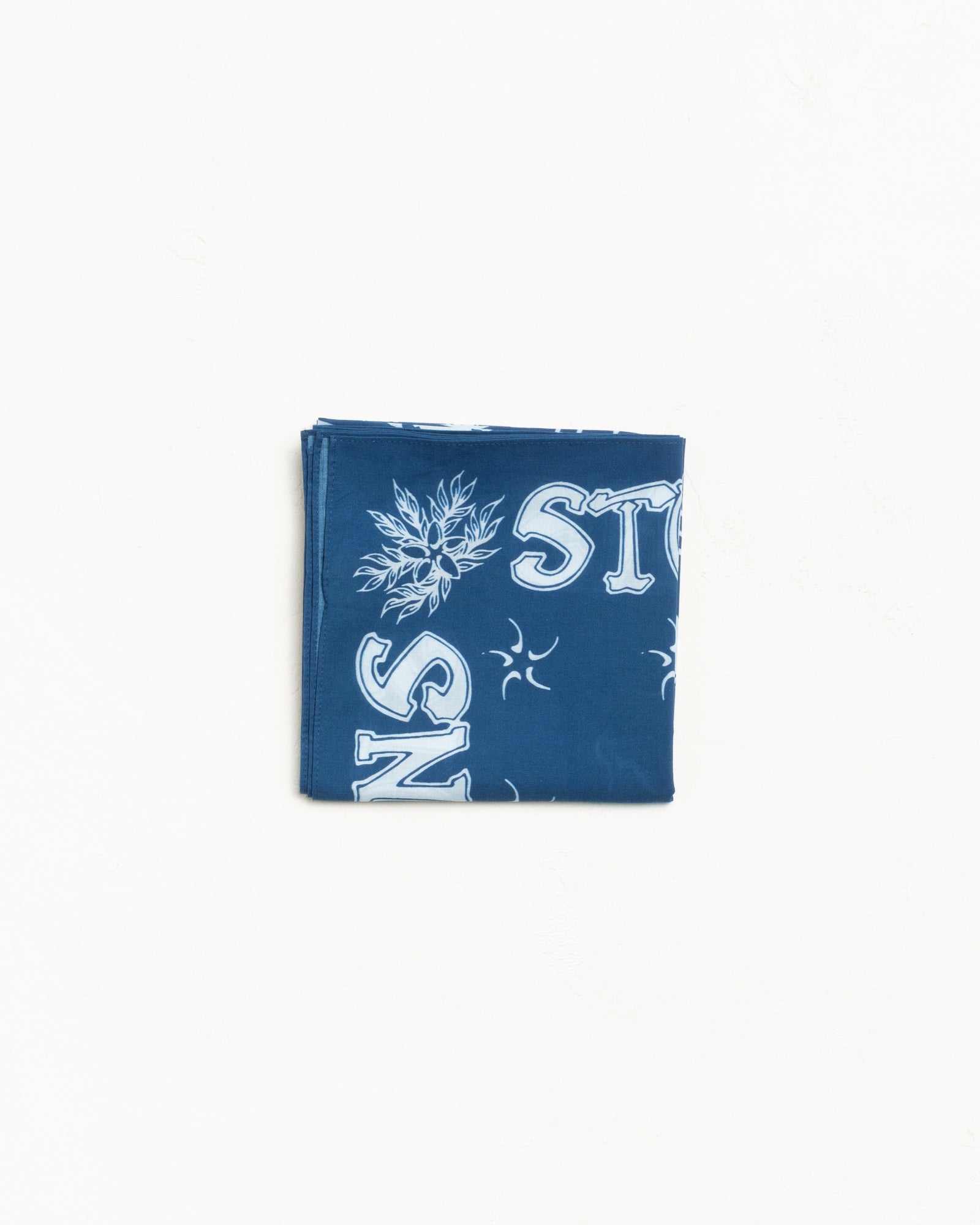 Blue folded bandana with white graphic print details on a white background