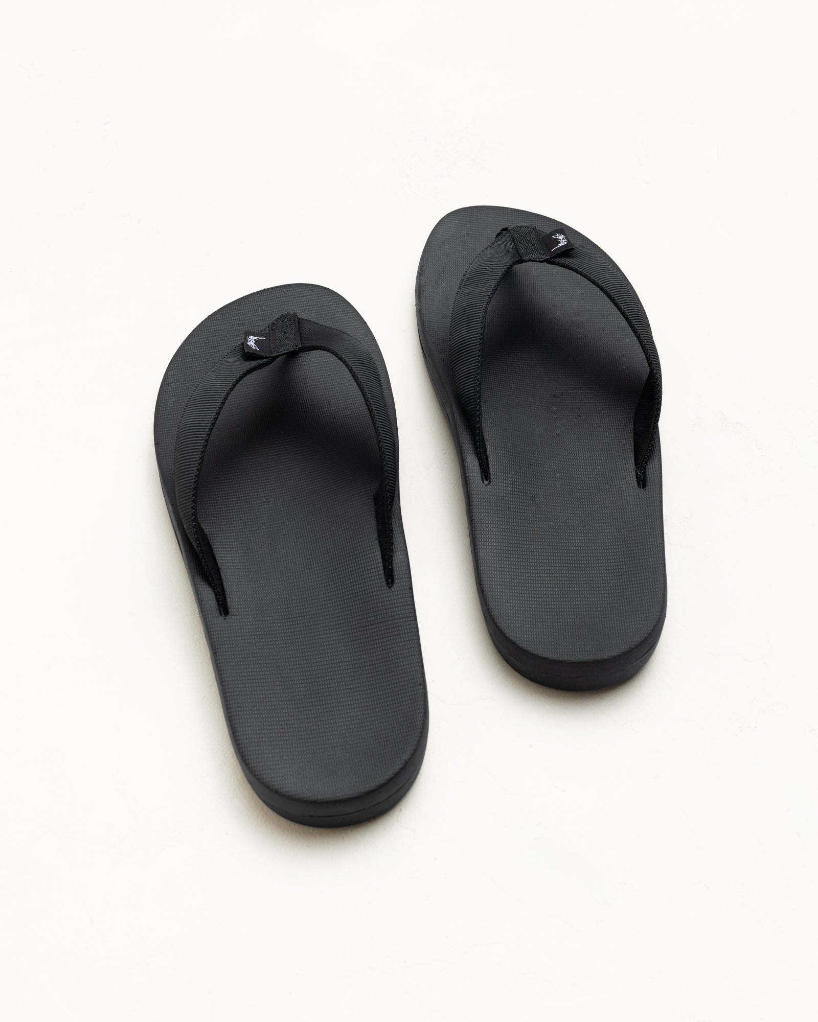 Unisex Rubber Flip-Flops In Black With Nylon Webbing Straps, Top View on White