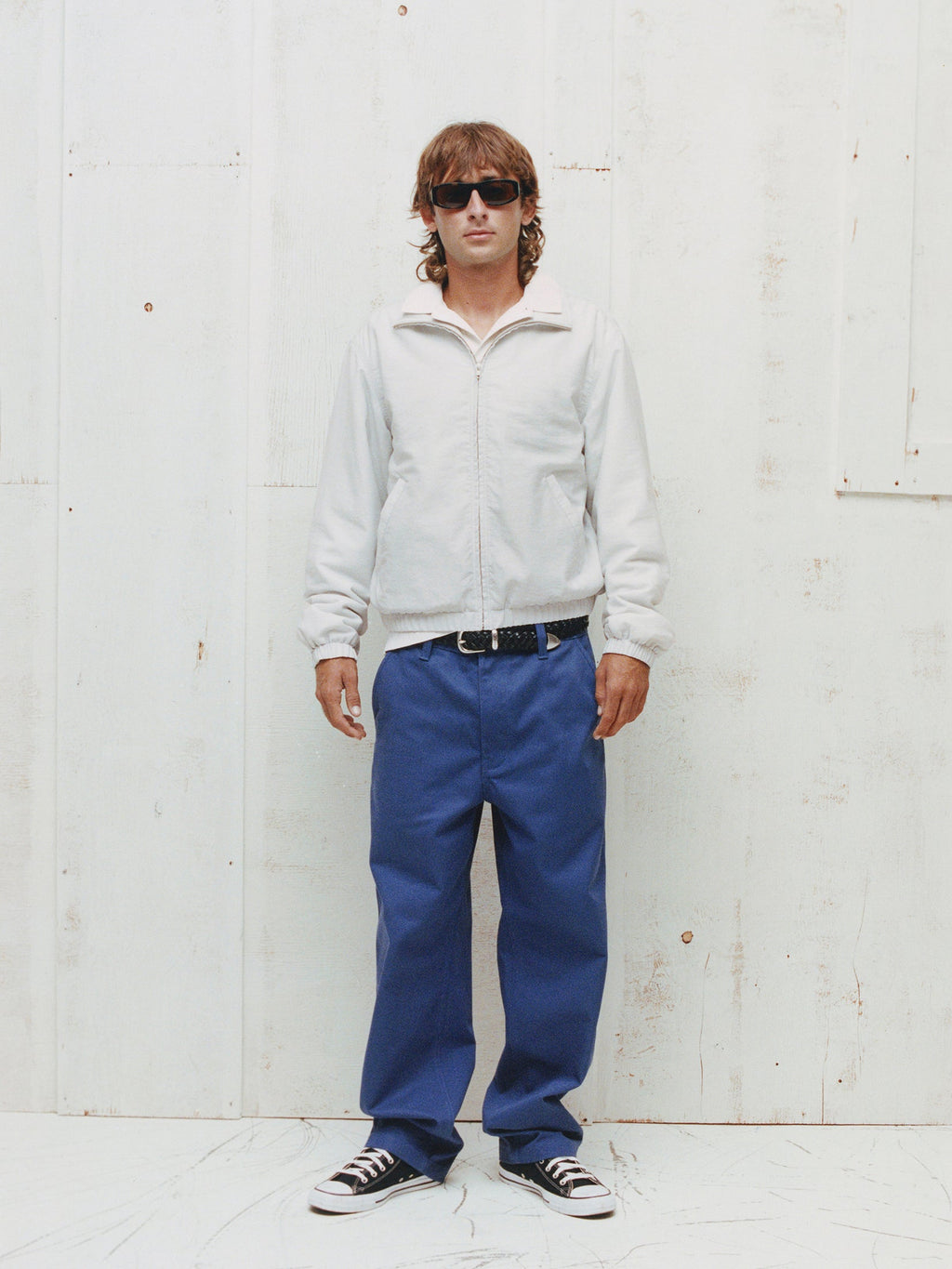 Model wears the Stüssy Swing Jacket in Ice with blue jeans, a black belt and black-and-white sneakers.